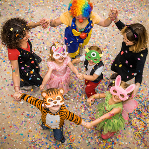 Maskierte Kinder und Betreuungspersonen tanzen im Kreis